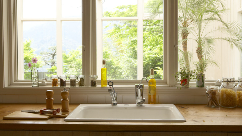 A kitchen sink with windows behind it