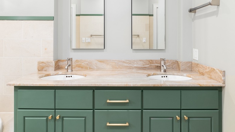 bathroom with light green walls dark green cabinets