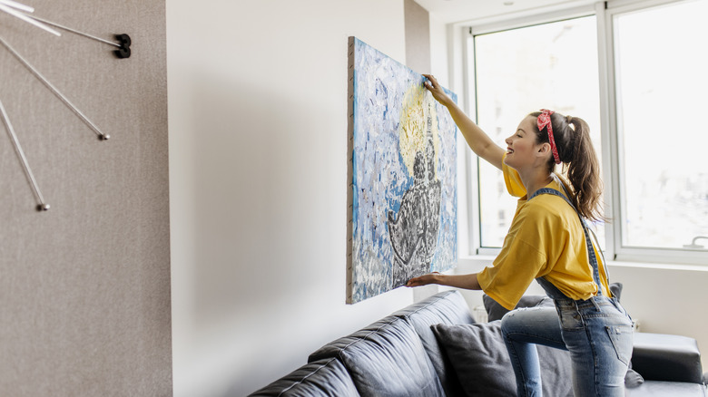 person hanging up artwork in her living room