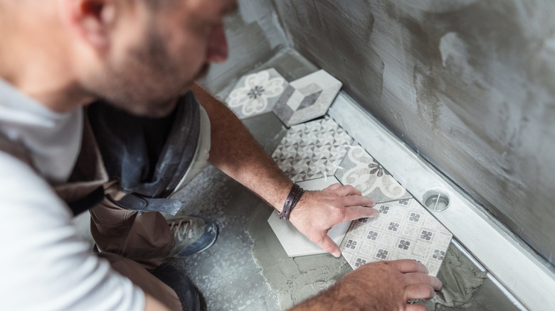 A person laying a tile floor