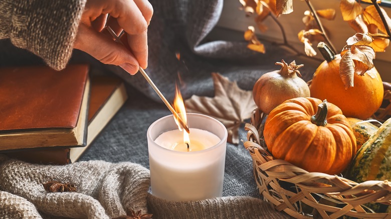 woman lighting a fall candle