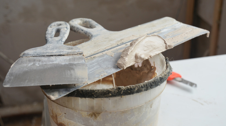 bucket of joint compound with scraper