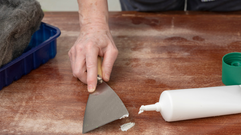 person fixing hardwood floor scratch 