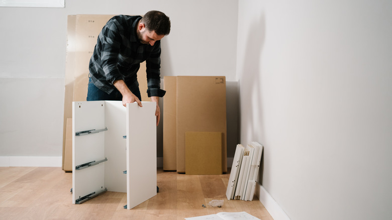 man assembles ikea drawer