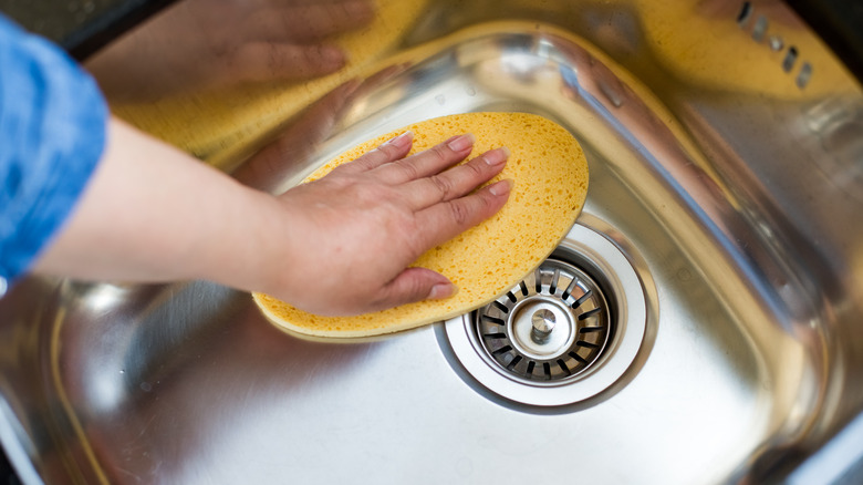 person wiping down sink 