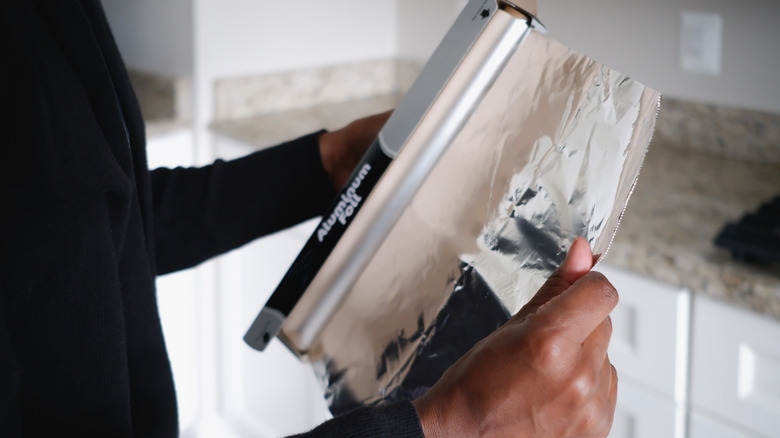 person tearing aluminum foil