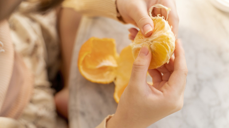 person peeling orange 