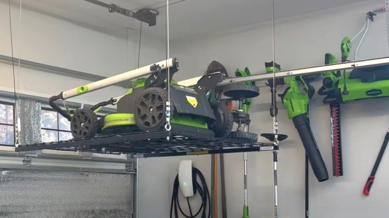 lawnmower on metal lifting garage ceiling storage rack