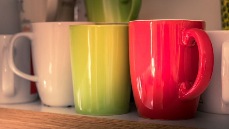 Close up of mugs stacked in cabinet.