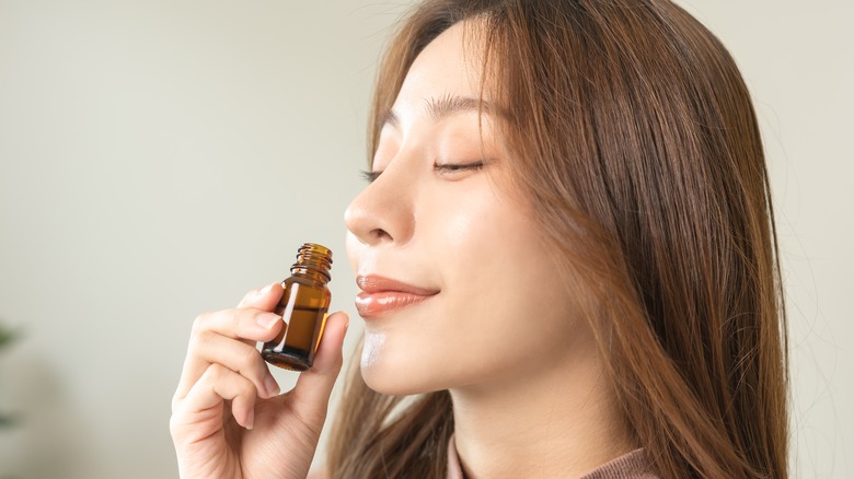 woman smelling essential oil bottle