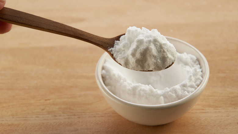 Spoon of baking soda scooped out of small bowl