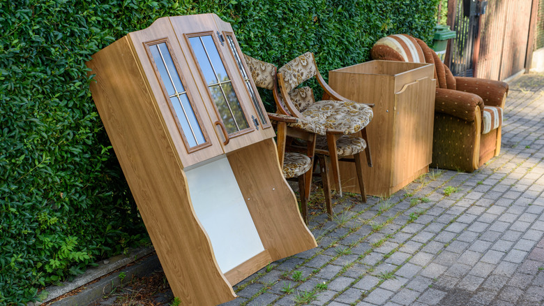 Vintage furniture lined up outside in front of greenery