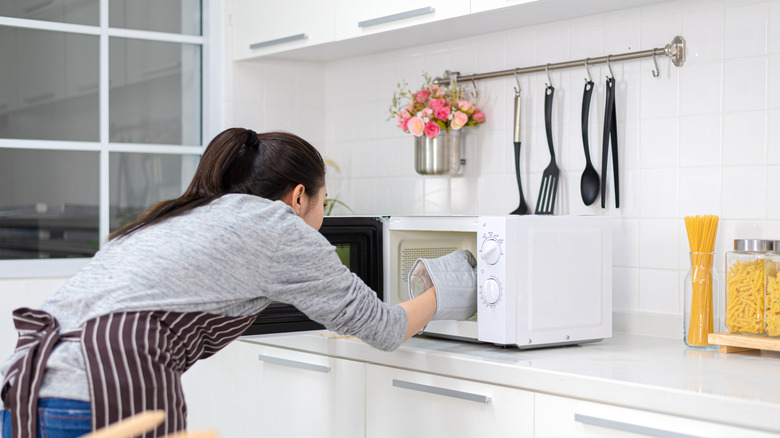 woman putting food in microwave