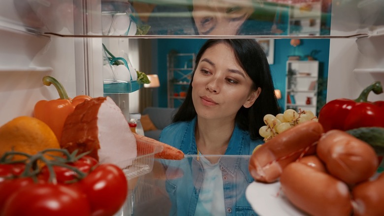 Woman sadly looking inside fridge