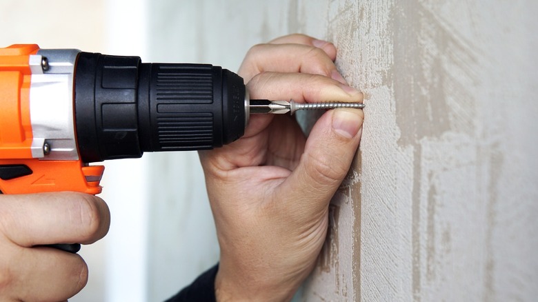 Close-up view of a person drilling a screw into a wall