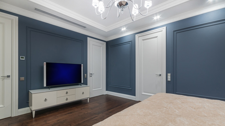 This is a luxurious bedroom painted dark blue-gray with white-painted doors.