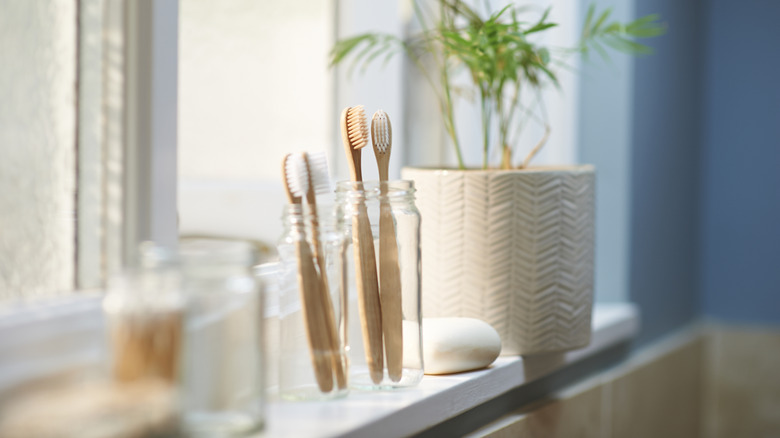 Bamboo toothbrushes in a glass jar on the window sill.