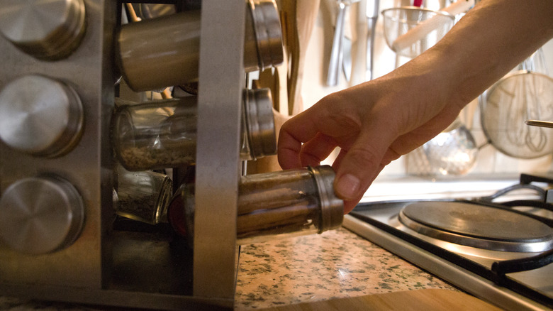 person reaching for spice rack