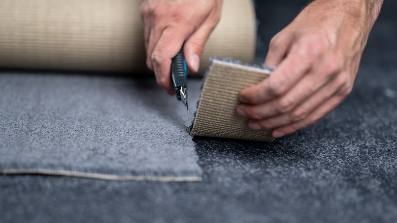 Hands cutting carpet