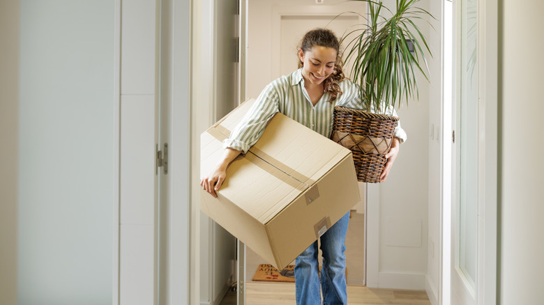 A woman holding a large cardboard box