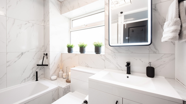 A white bathroom is fitted with black décor