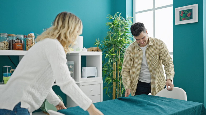 couple putting tablecloth on table