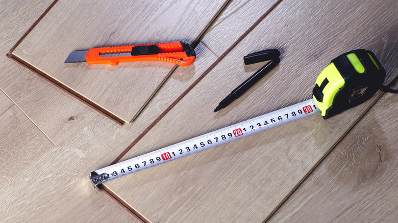 Measuring and cutting tools laying on pieces of vinyl flooring