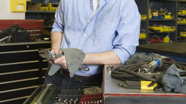 Man wiping tool by toolbox