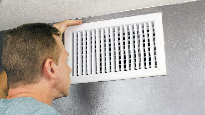 Man inspecting wall register