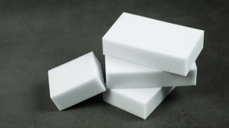 A stack of white melamine sponges rest on a dark surface