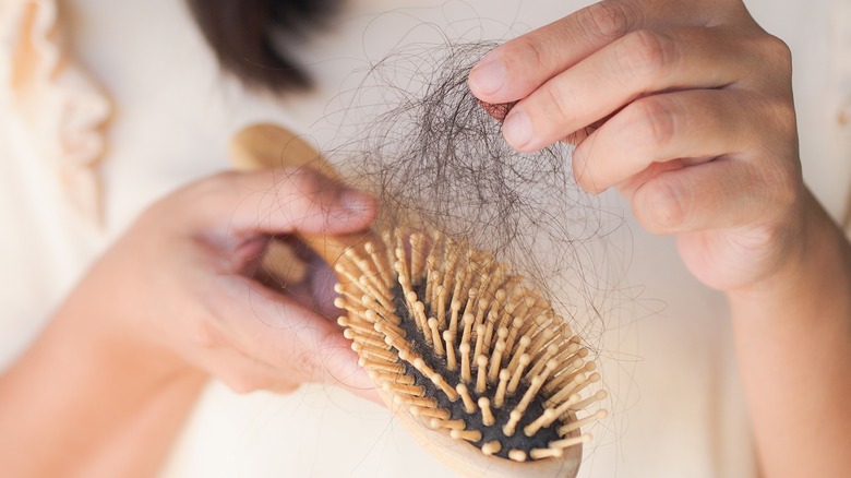 person pulling hair from brush