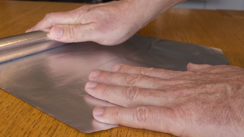 Man rolling out aluminum foil