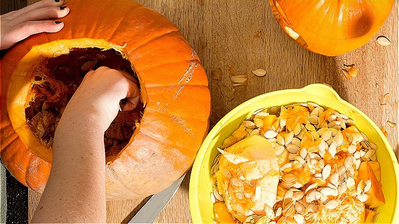 Person cleaning out a pumpkin