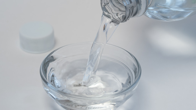 Pouring transparent liquid in bowl