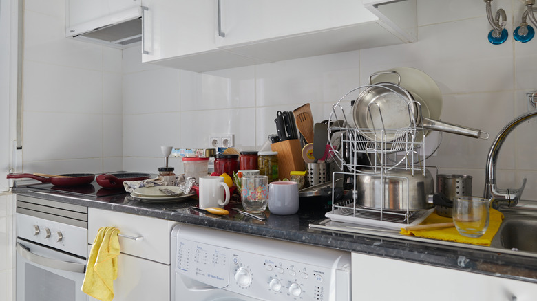 A cluttered kitchen countertop with dishes strewn everywhere