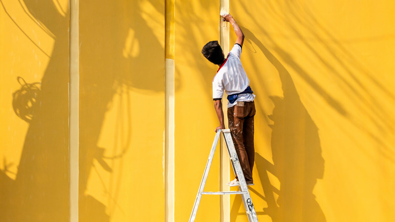 Man painting a large exterior wall.