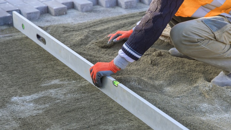 person dragging a leveling board over sand