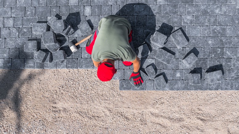 man laying paver stones over sand