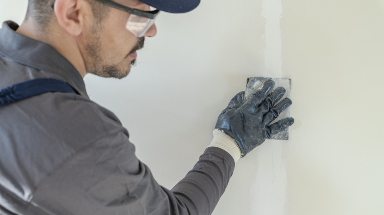 man filling cracks in wall