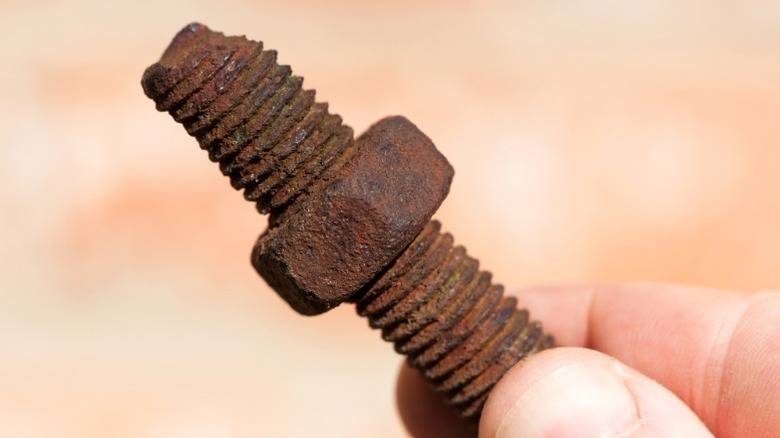 closeup of rusted nut and bolt in person's hand