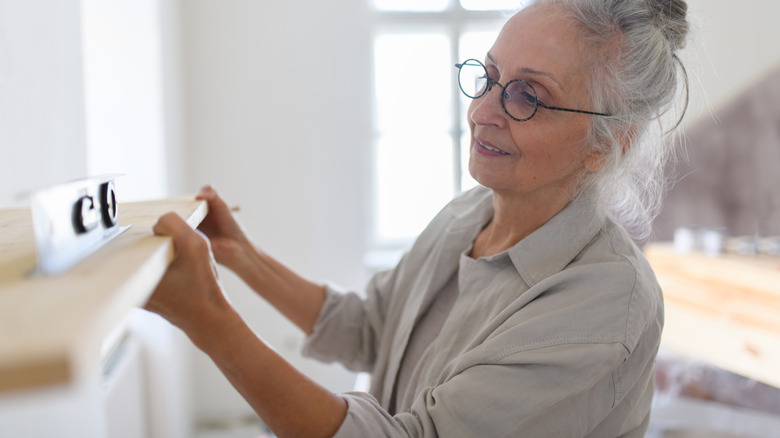 A woman is using a level to ensure a shelf is even