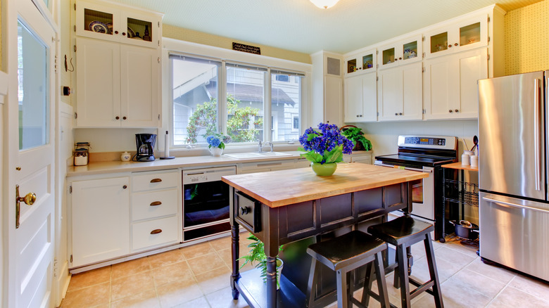 Dark furniture used as an island in a white kitchen