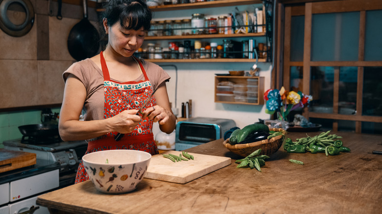 A woman cutting vegetables at a kitchen island