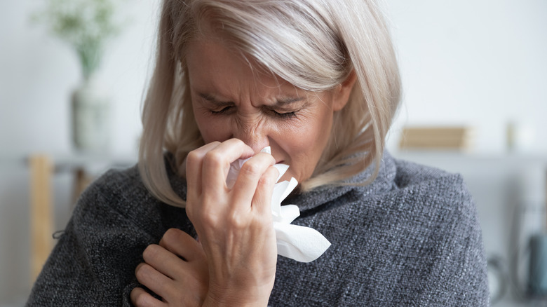 woman holding tissue to nose