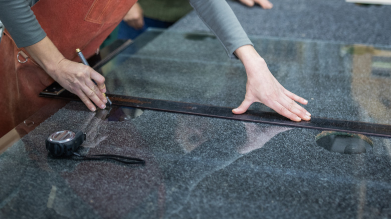 Person measuring and cutting glass