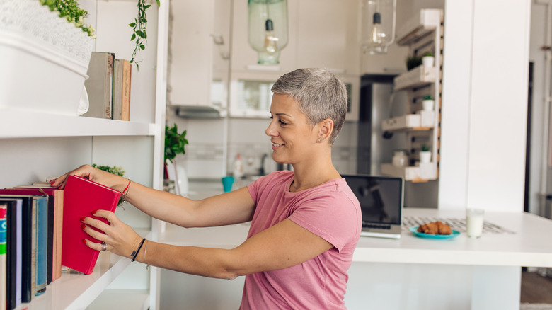 woman pulling book off shelf