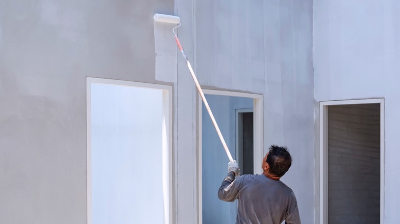 person painting a wall with roller