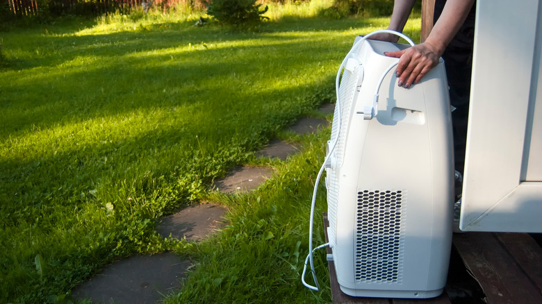 person moving portable air conditioner into house