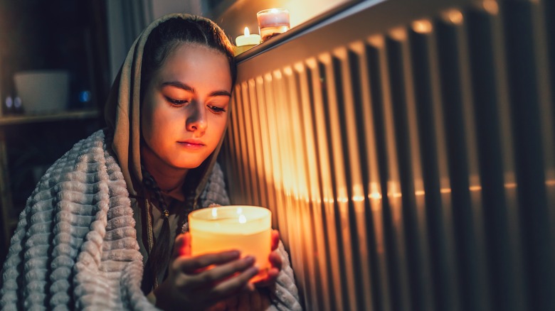 A woman sits by a radiator 