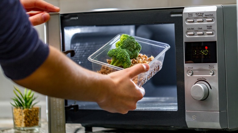 Man putting plastic in microwave 